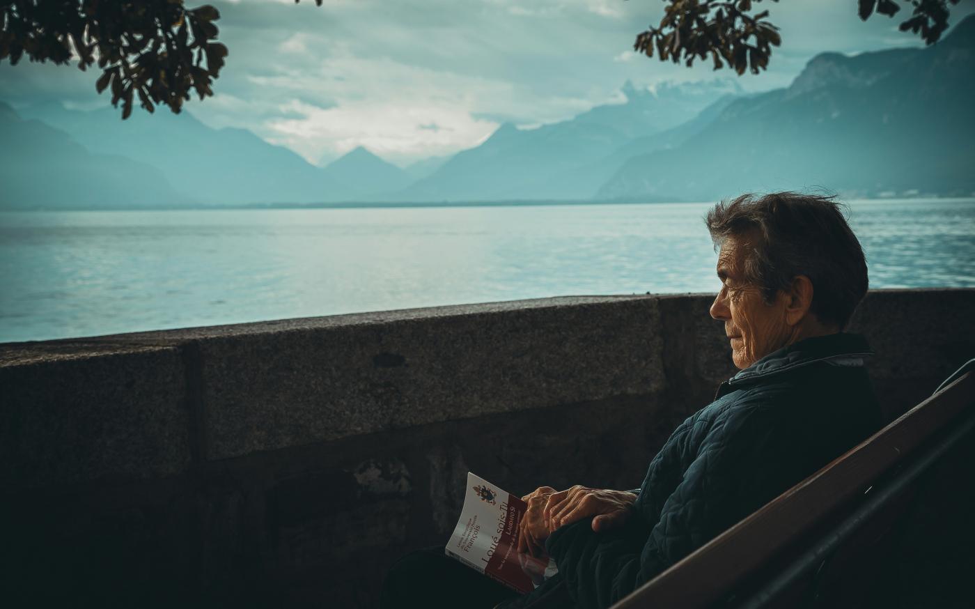 man sitting while holding a book watching on body of water by Aaron Andrew Ang courtesy of Unsplash.