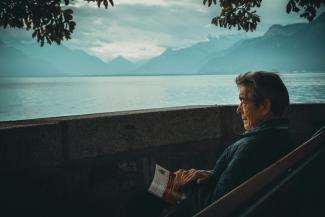 man sitting while holding a book watching on body of water by Aaron Andrew Ang courtesy of Unsplash.