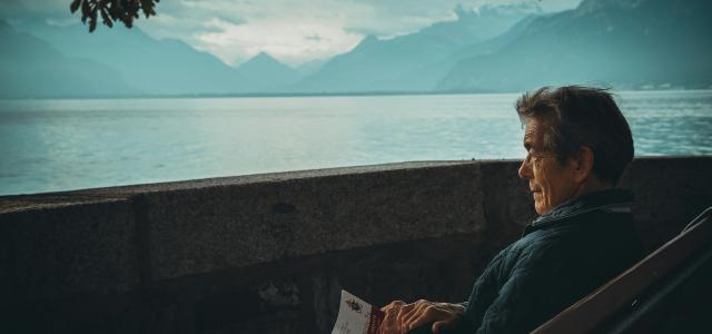 man sitting while holding a book watching on body of water by Aaron Andrew Ang courtesy of Unsplash.